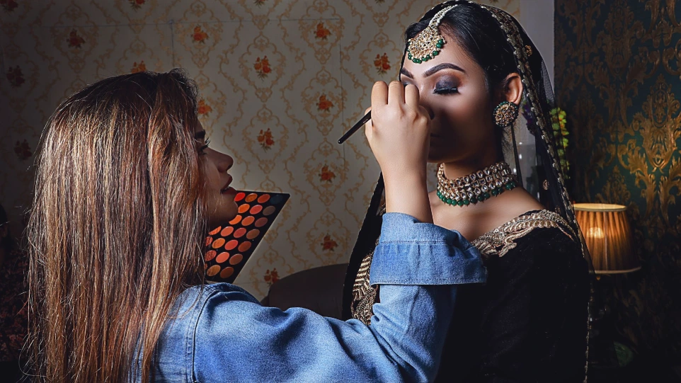 a woman putting makeup on another woman's face